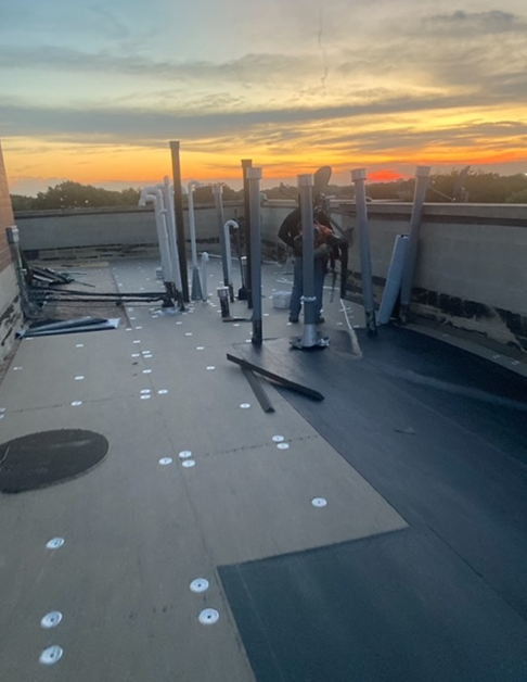 a man is working on the roof of a building at sunset
