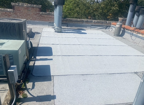 the roof of a building with a gray roof and a green air conditioner
