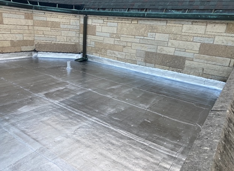 a roof with a drain pipe and a brick wall in the background