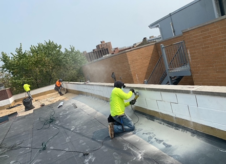 a man is kneeling on a roof with a drill .