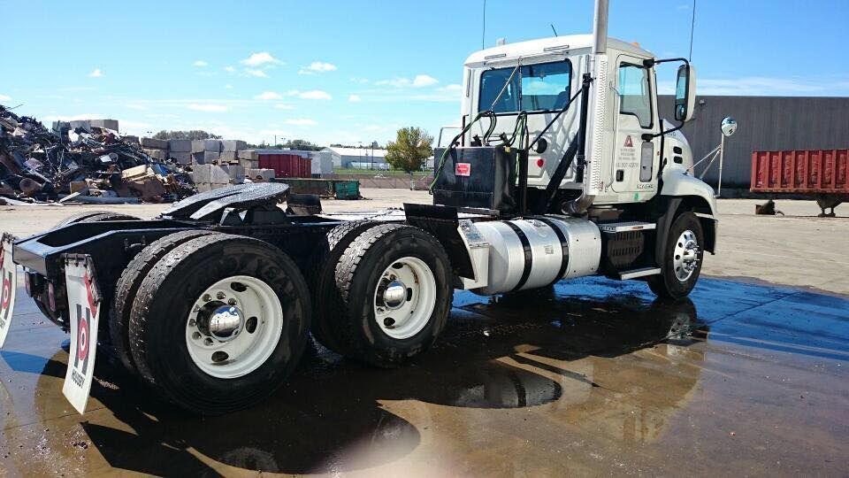 A semi truck with a trailer attached to it is parked in a parking lot.