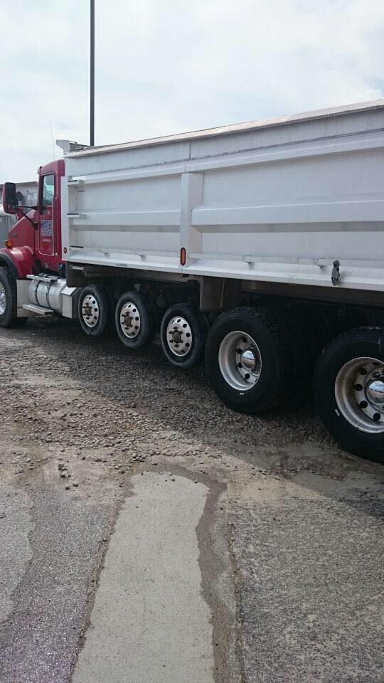 A red and white dump truck is parked on the side of the road.