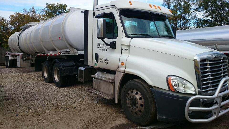A white semi truck is parked in a gravel lot.