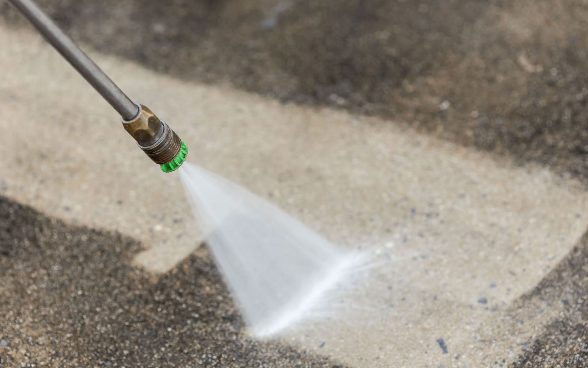 A person is using a high pressure washer to clean a concrete floor.