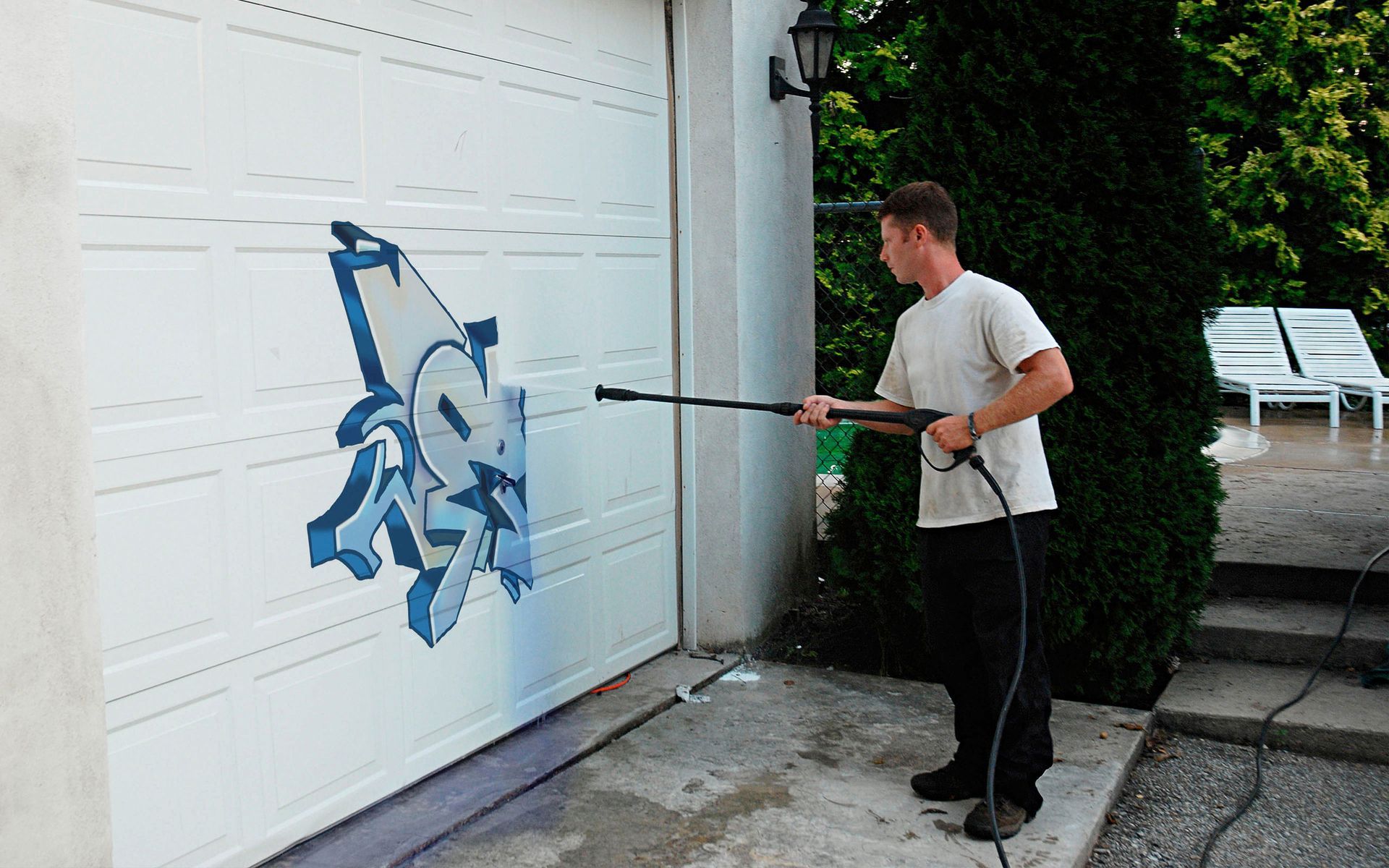 A man is cleaning a garage door with a high pressure washer