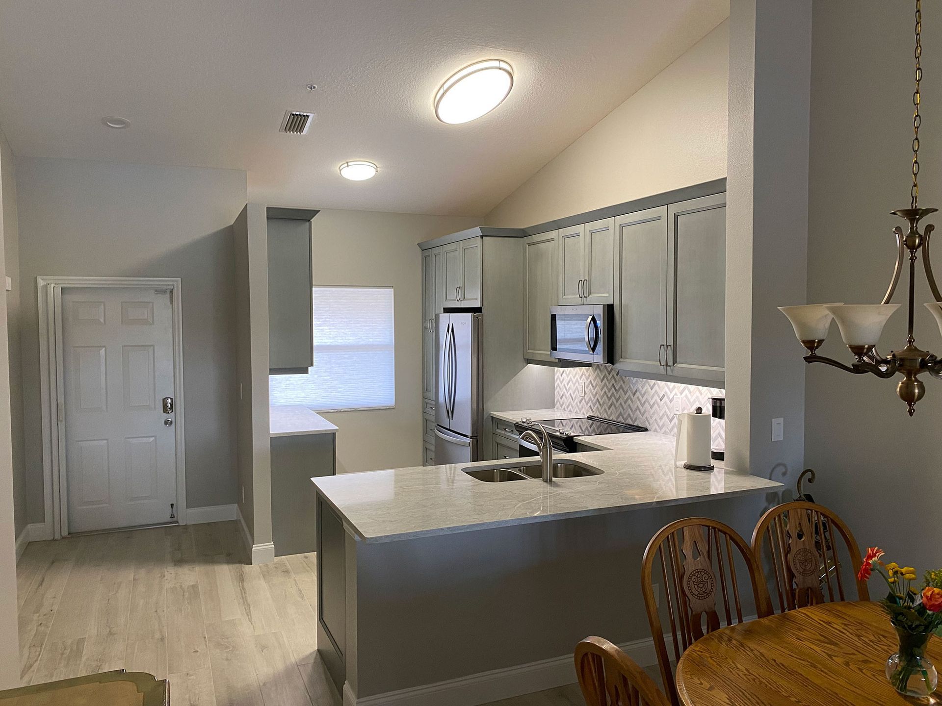 Kitchen with gray cabinets, white countertops, and a dining table.
