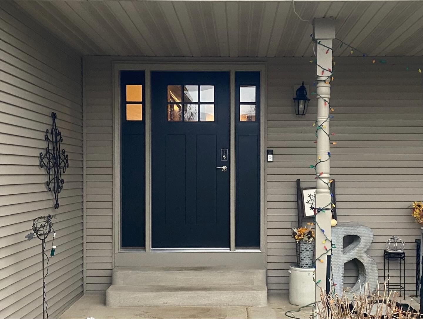 Front porch with navy double door, beige siding, and Halloween decorations