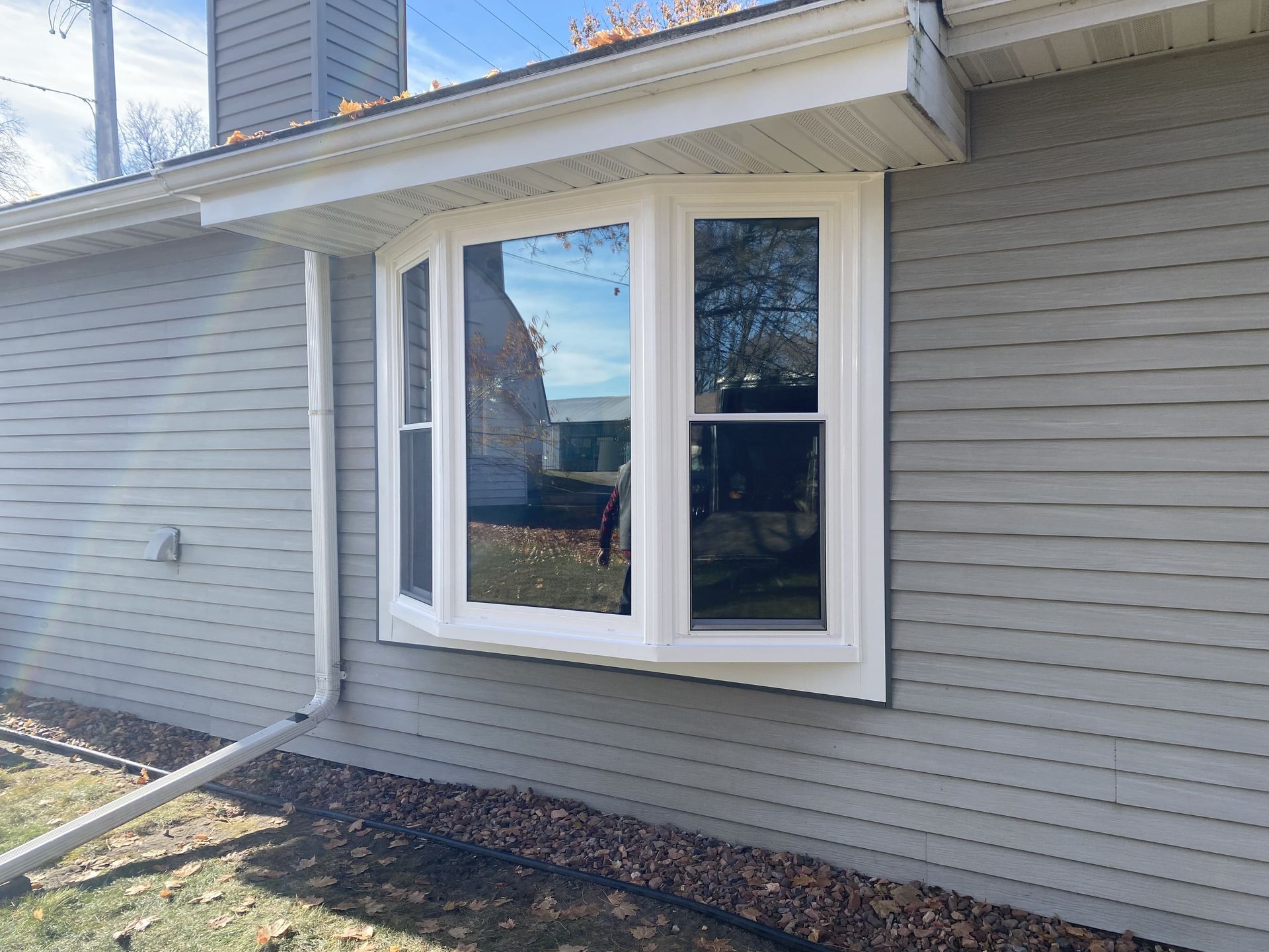 House exterior with gray siding and a white bay window under a small roof overhang