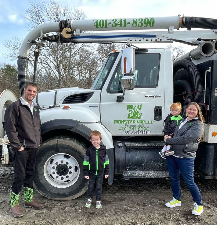 A family is standing in front of a vacuum truck.