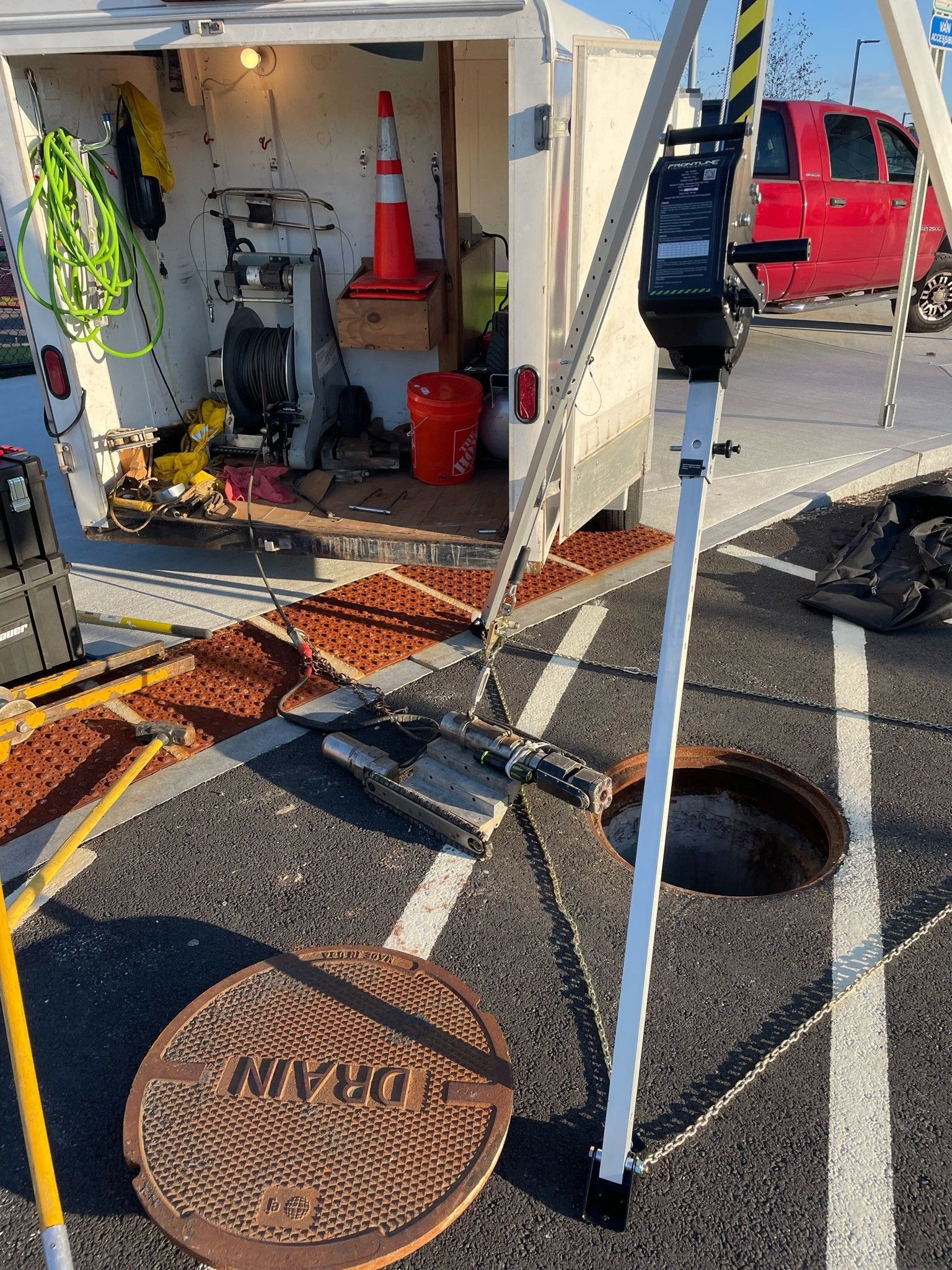 A manhole cover is sitting in a parking lot next to a trailer.