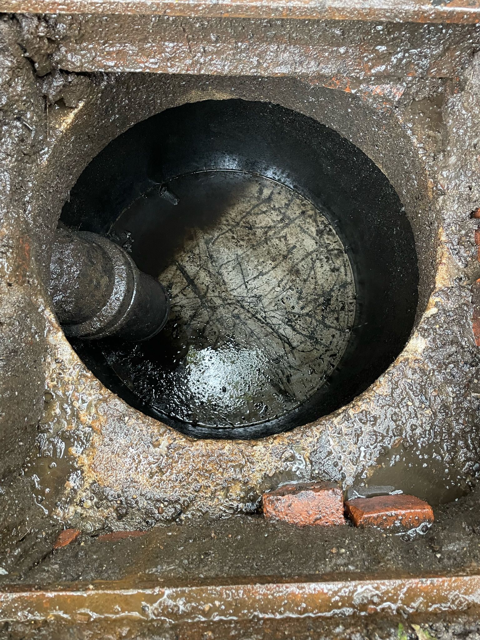 A close up of a hole in a drain with water coming out of it.