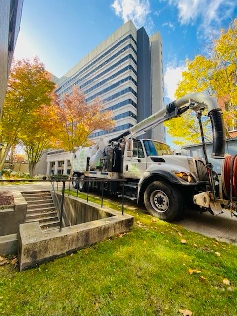A vacuum truck is parked in front of a building.