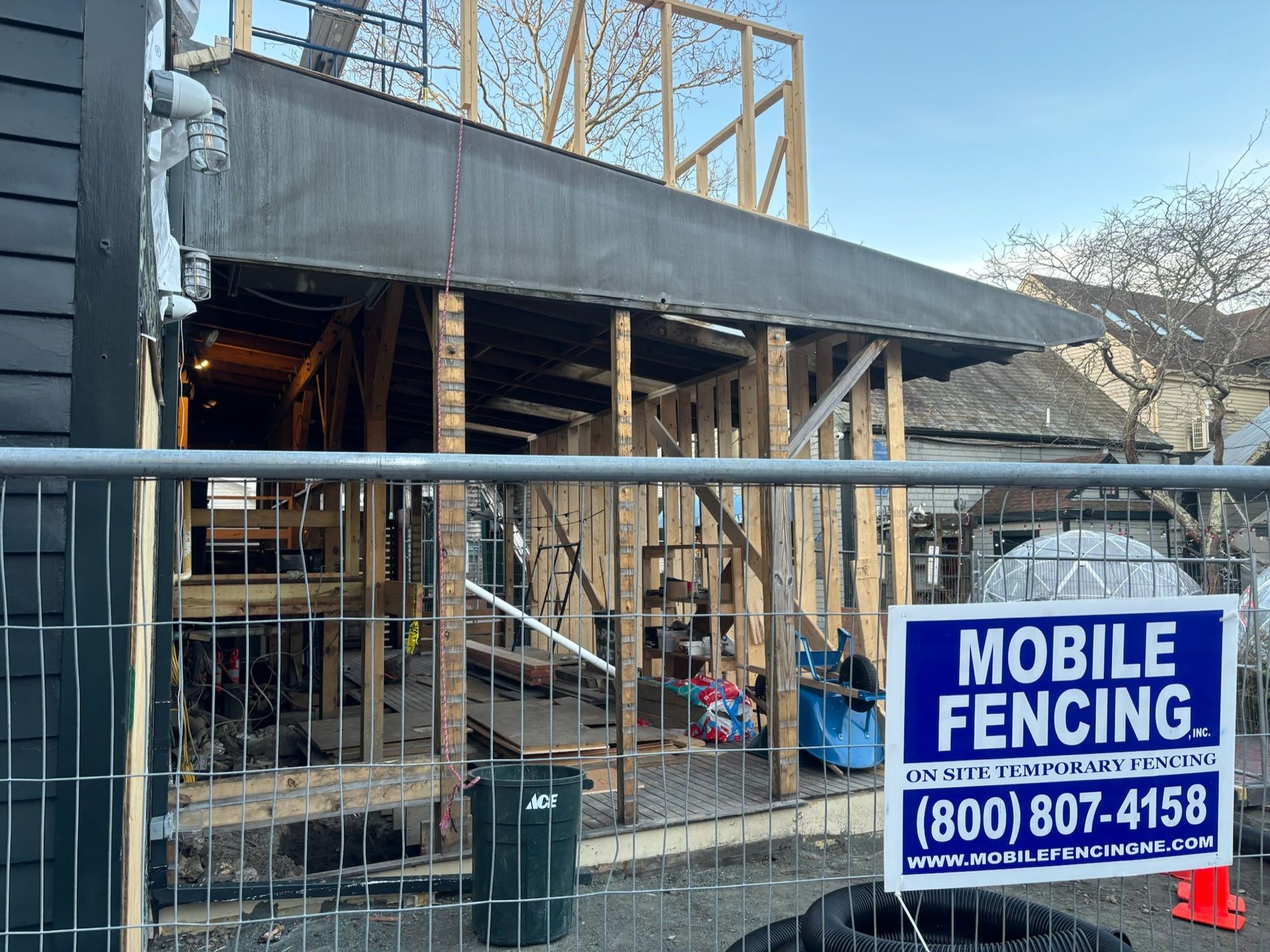 A building under construction with a mobile fencing sign in front of it.