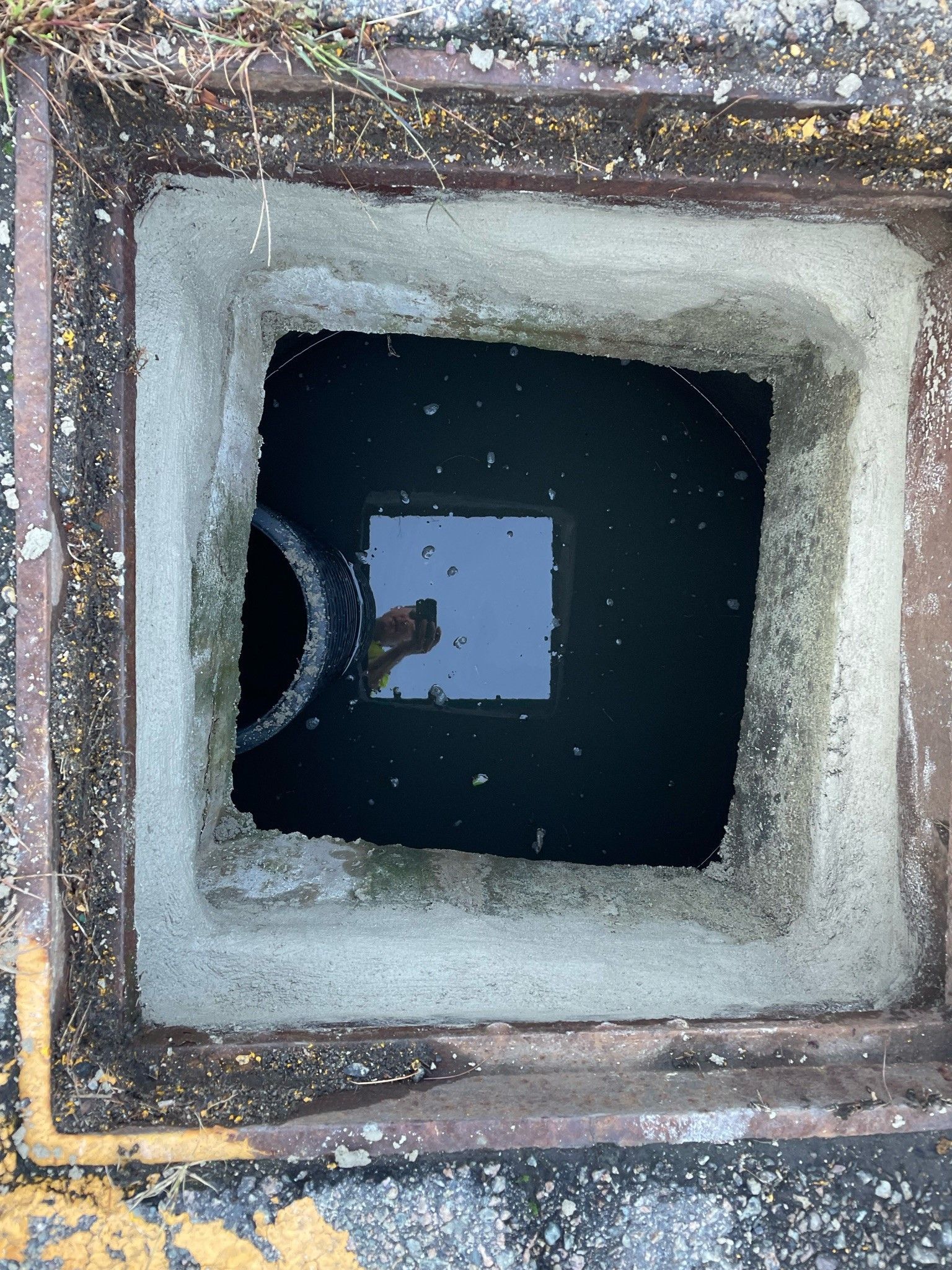 A manhole cover with a hole in it and water coming out of it.