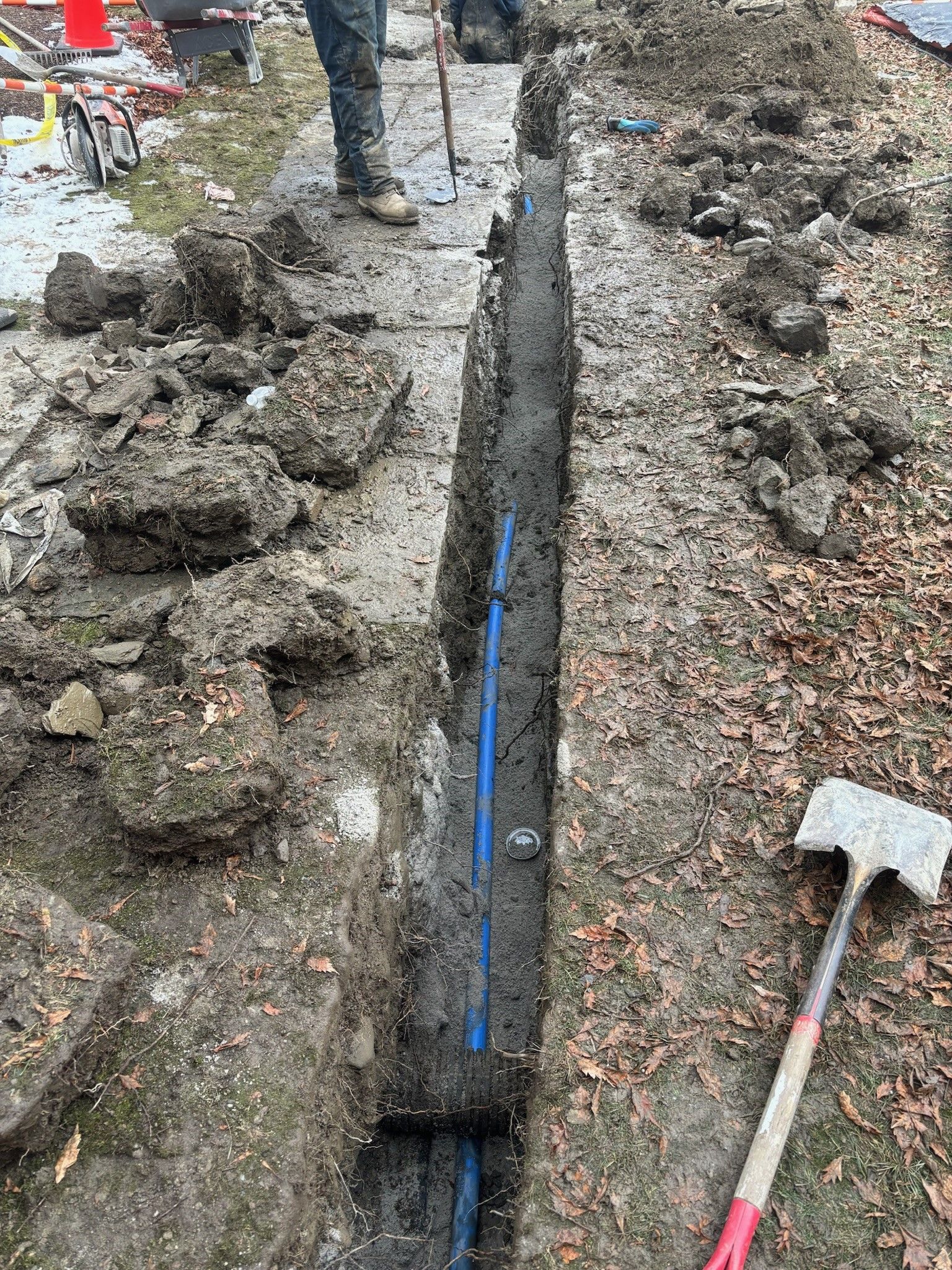 A man is digging a hole in the ground to install a pipe.