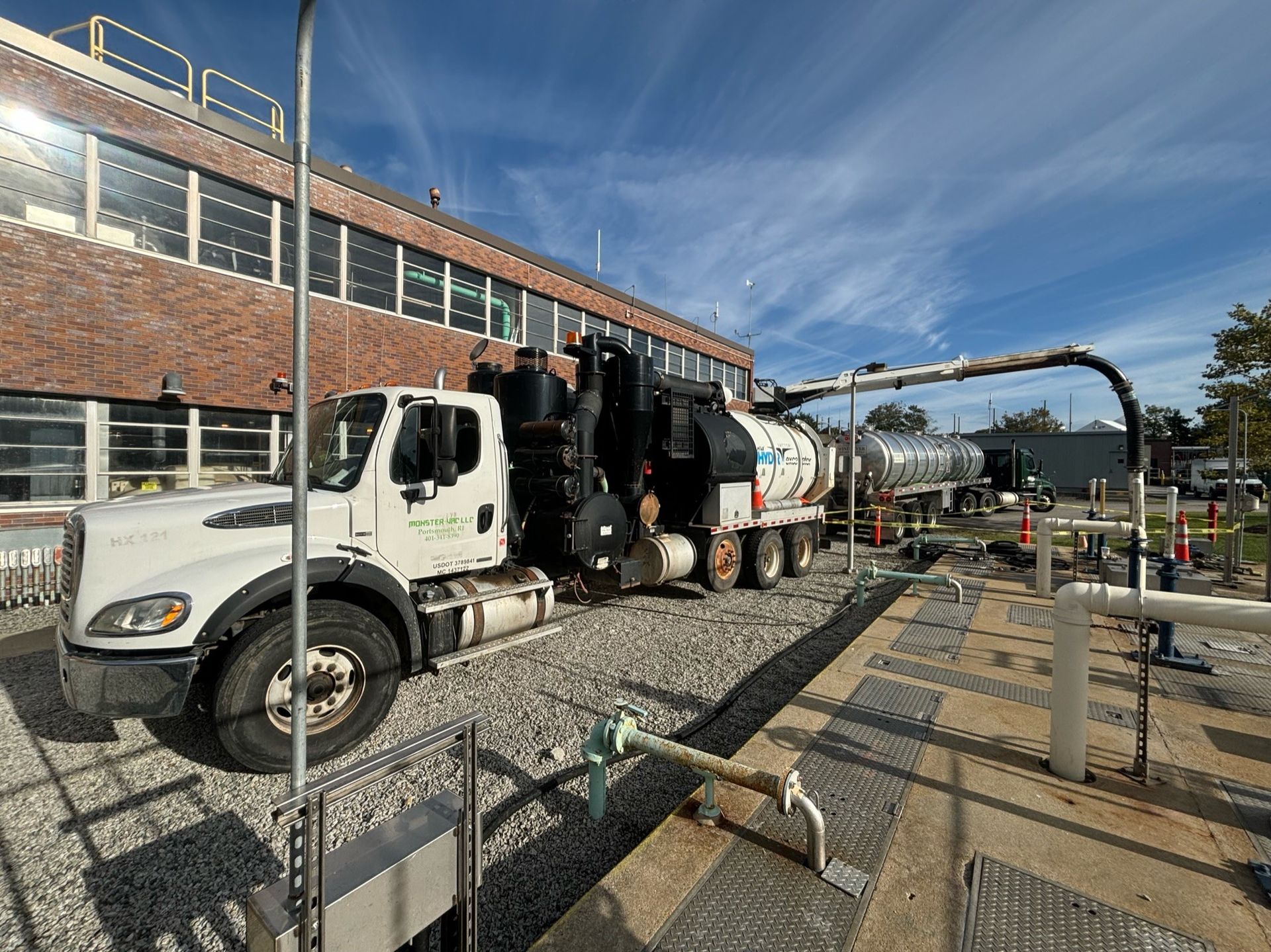 A vacuum truck is parked in front of a brick building.