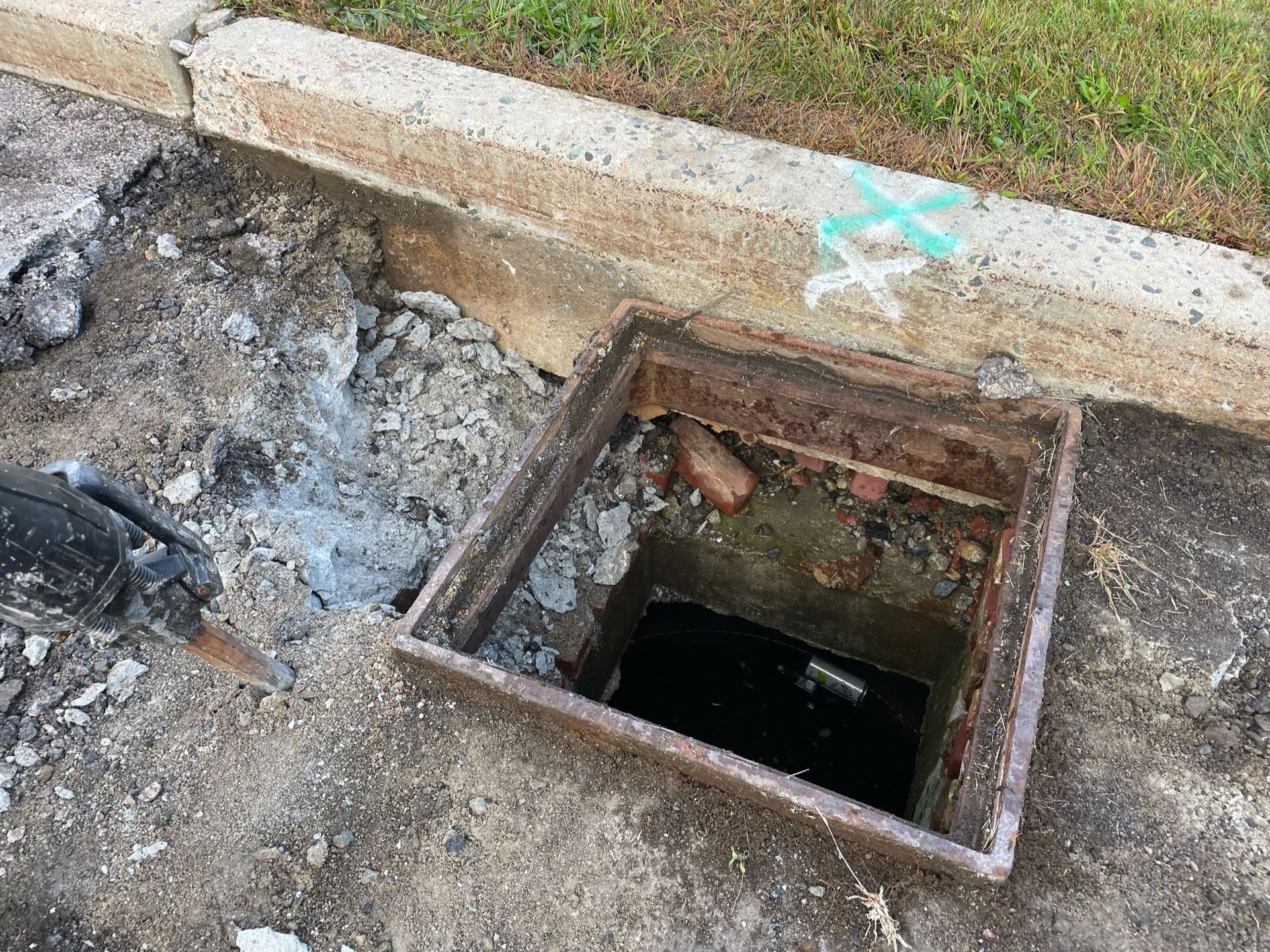A manhole cover is sitting on the ground next to a curb.