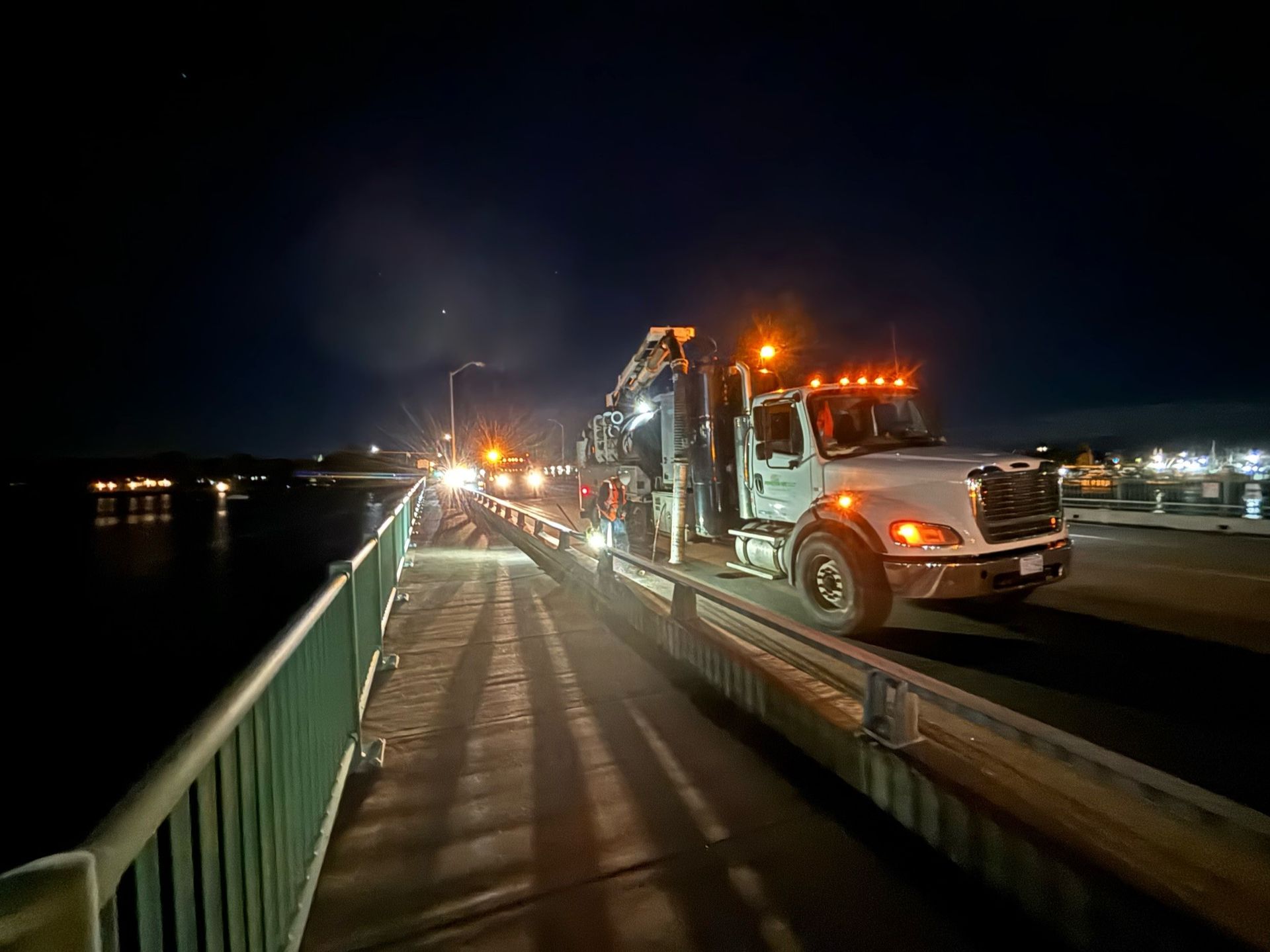 A truck is driving on a bridge at night.