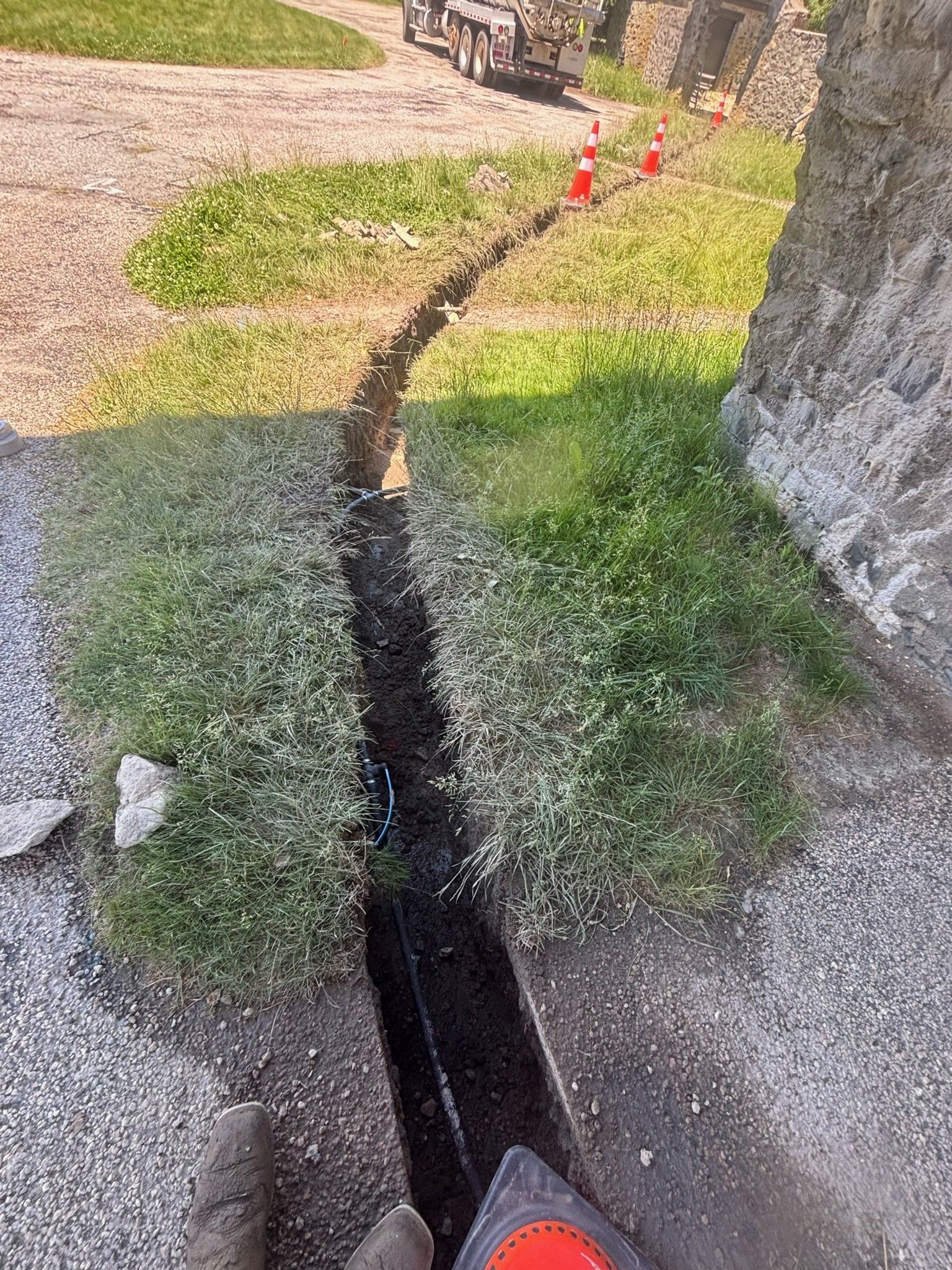 A person is holding a tape measure next to a drain on the side of a road.