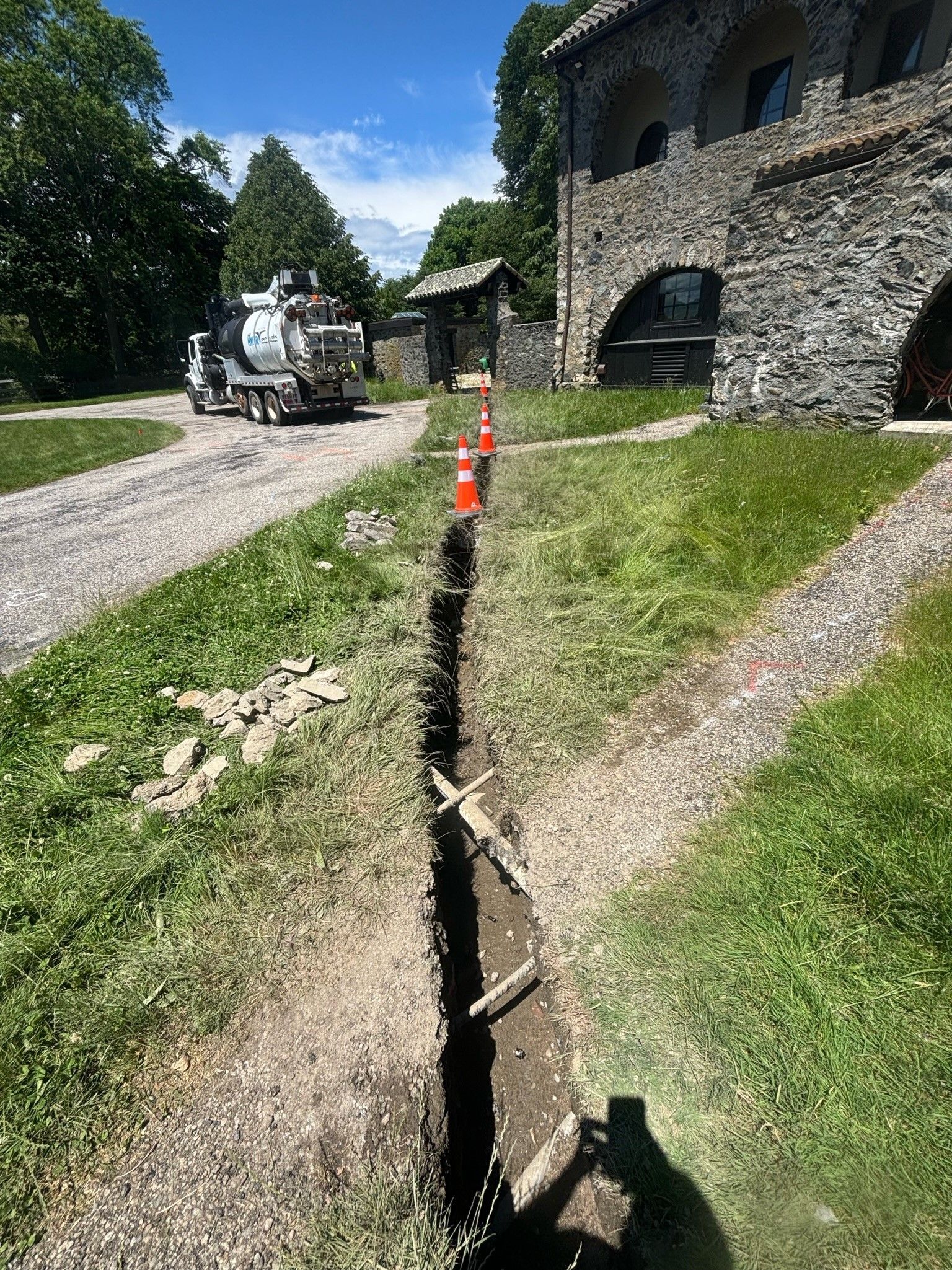 A truck is driving down a dirt road next to a stone building.