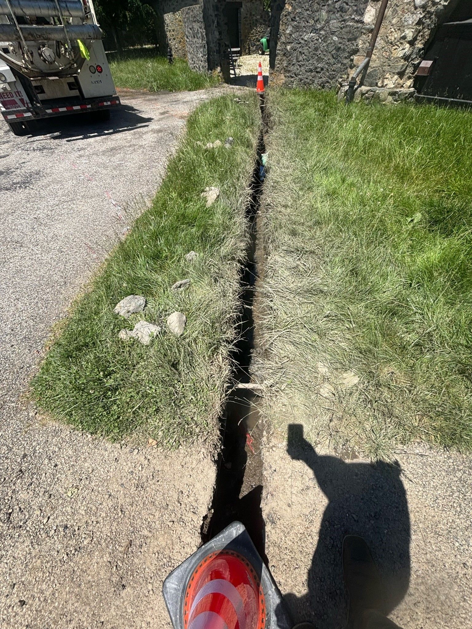 A truck is driving down a dirt road next to a grassy area.