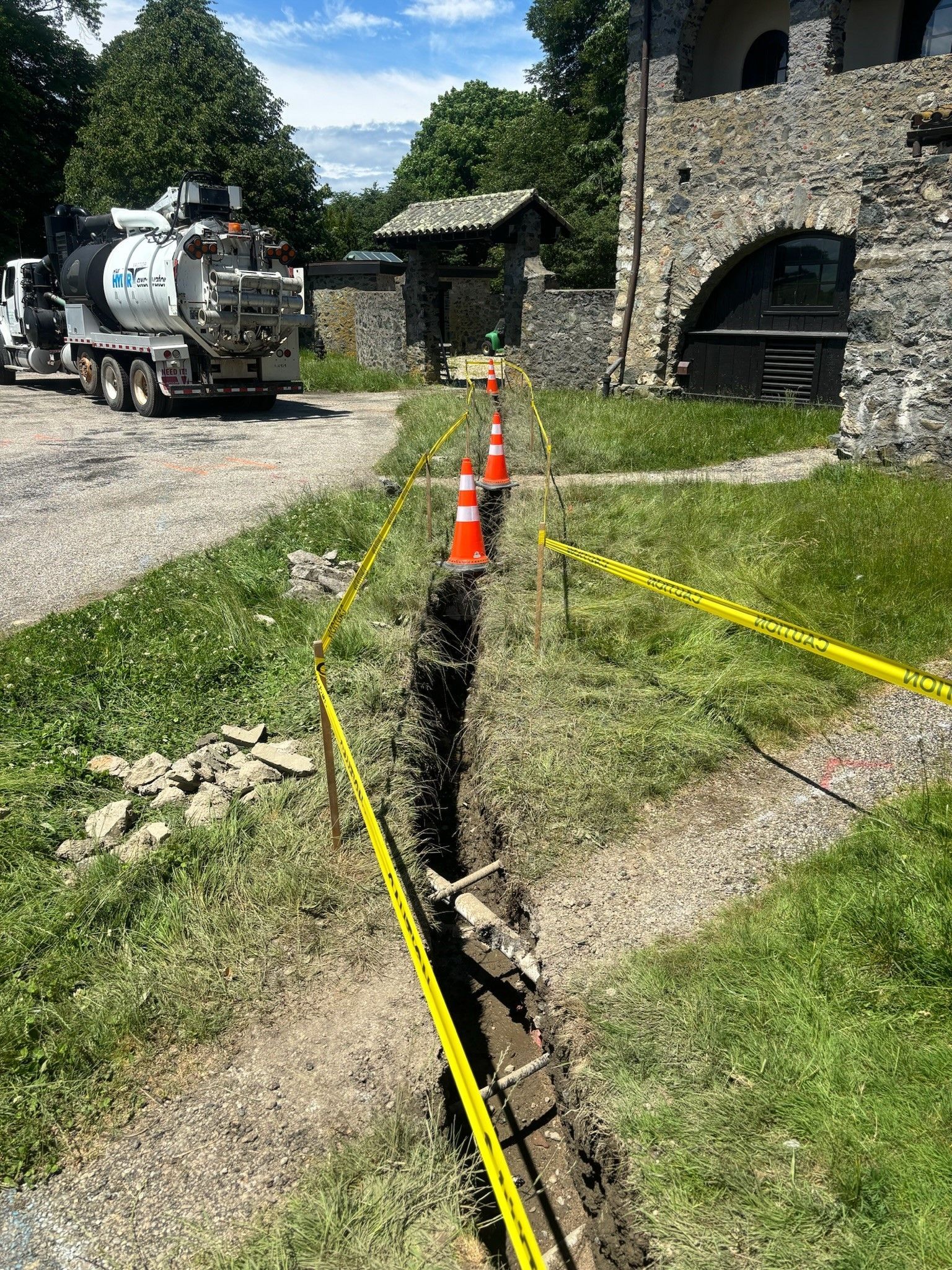 A truck is driving down a dirt road next to a stone building.