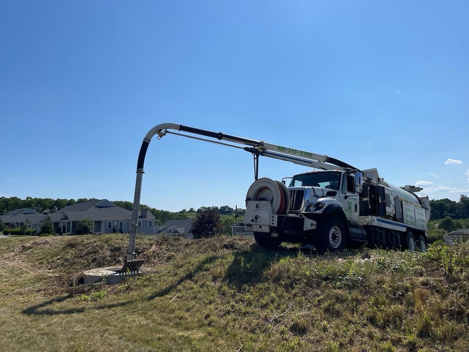 A vacuum truck is sitting on top of a grassy hill.