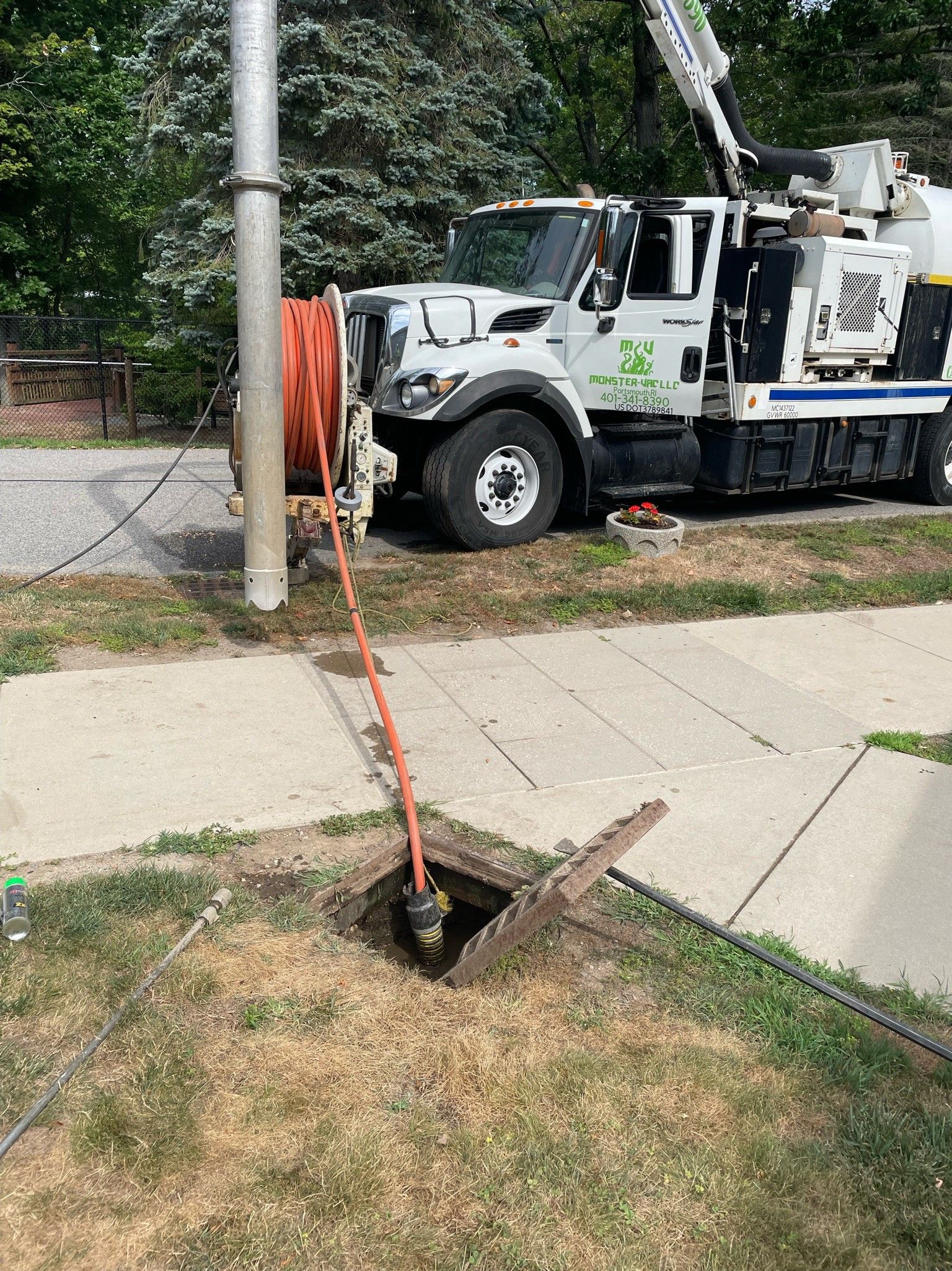 A white truck is parked on the side of the road next to a manhole cover.