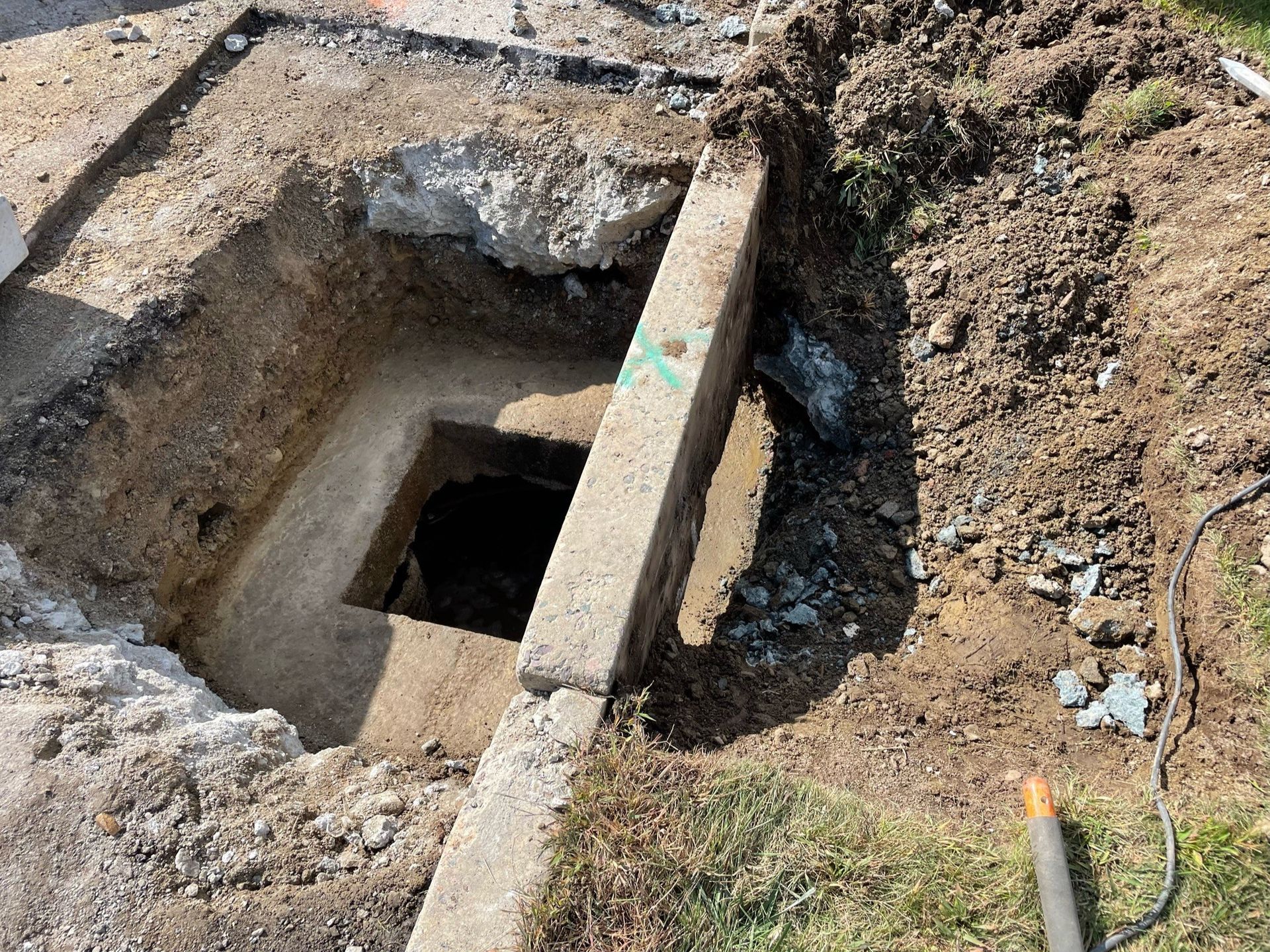 A hole in the ground with a shovel in it.