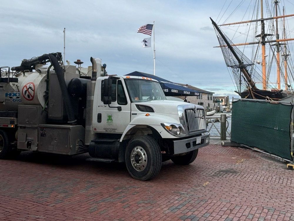 A vacuum truck is parked in front of a ship.