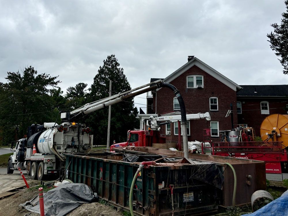 A vacuum truck is parked in front of a brick house