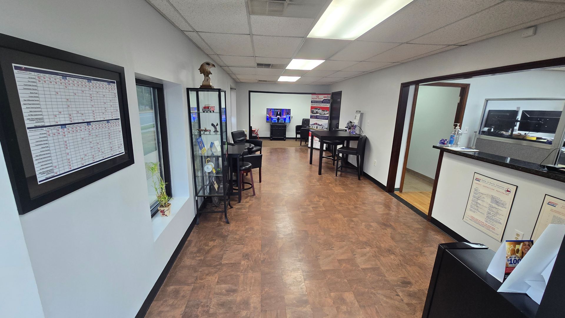 Long hallway in an office or clinic with framed documents, chairs, and counters along the walls.