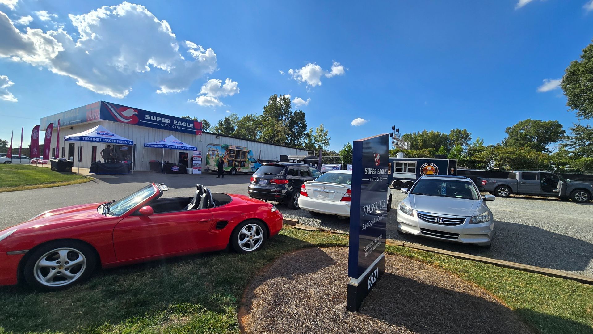 Red convertible and other cars parked outside a car dealership on a sunny day
