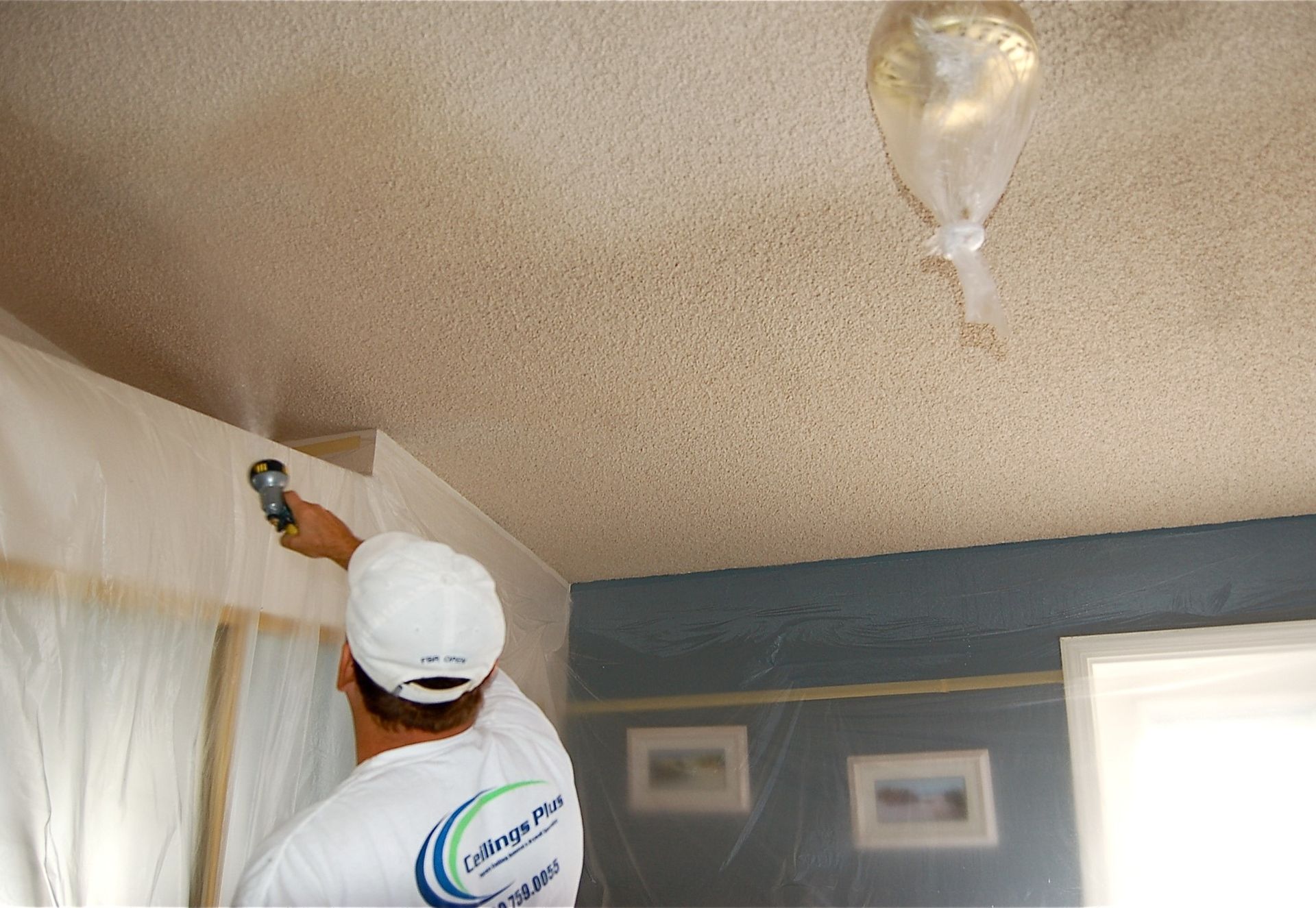 A man is painting the ceiling of a room