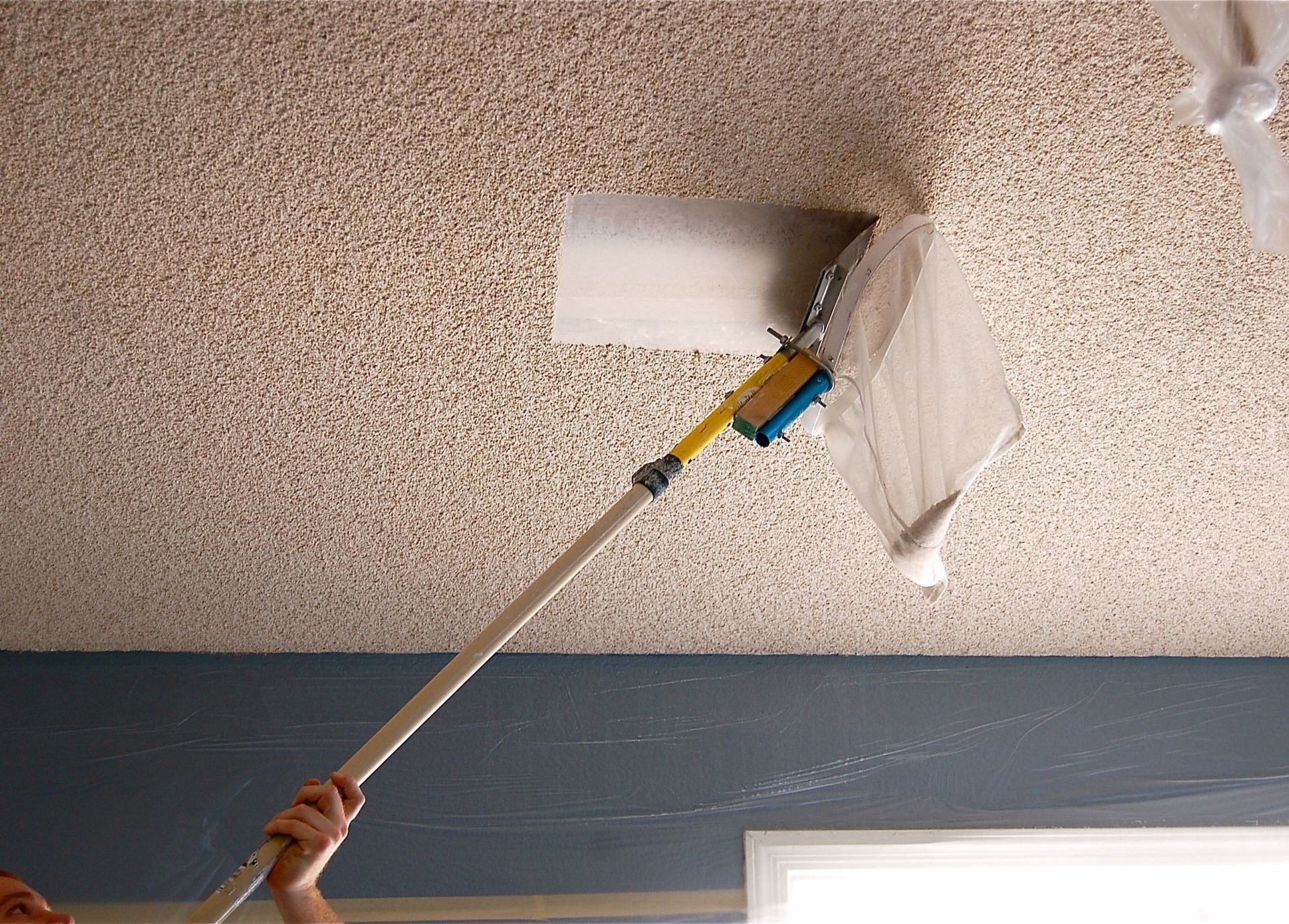 A person is painting a ceiling with a roller.
