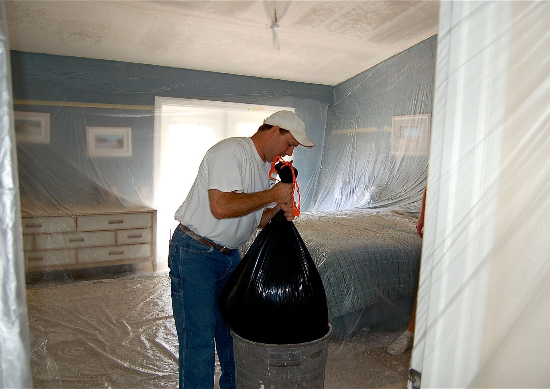 A man is holding a black trash bag in a room