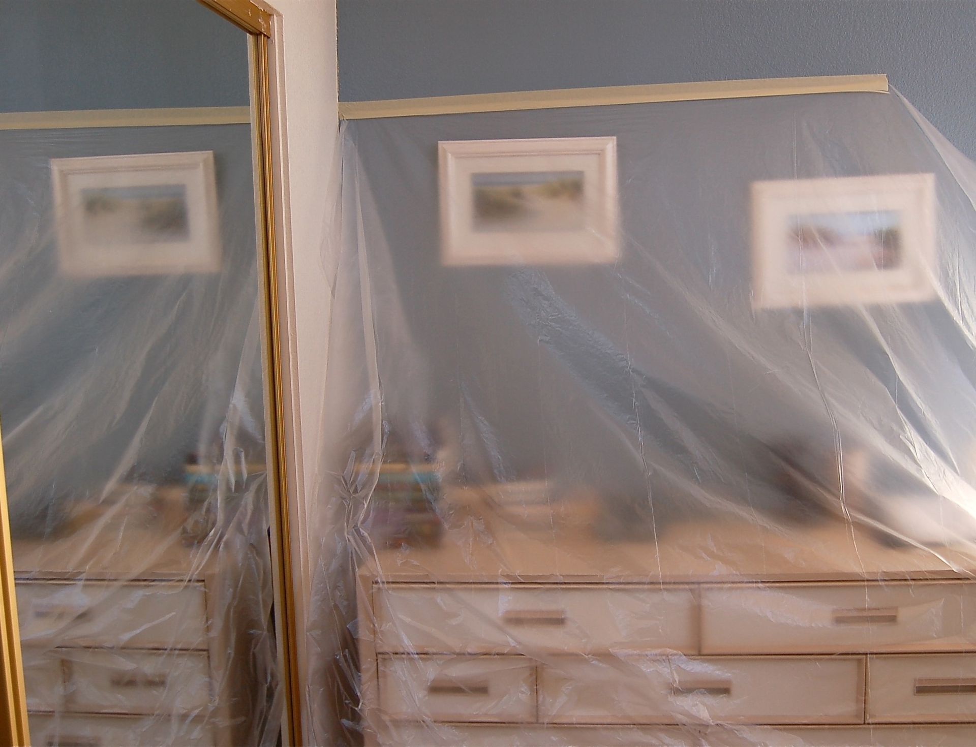 A room with a dresser and a mirror covered in plastic