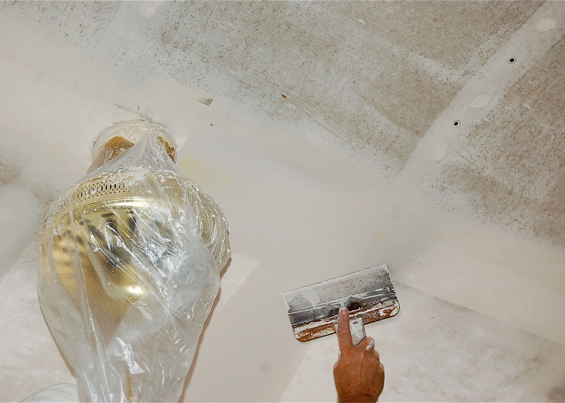 A person is painting a ceiling with a spatula