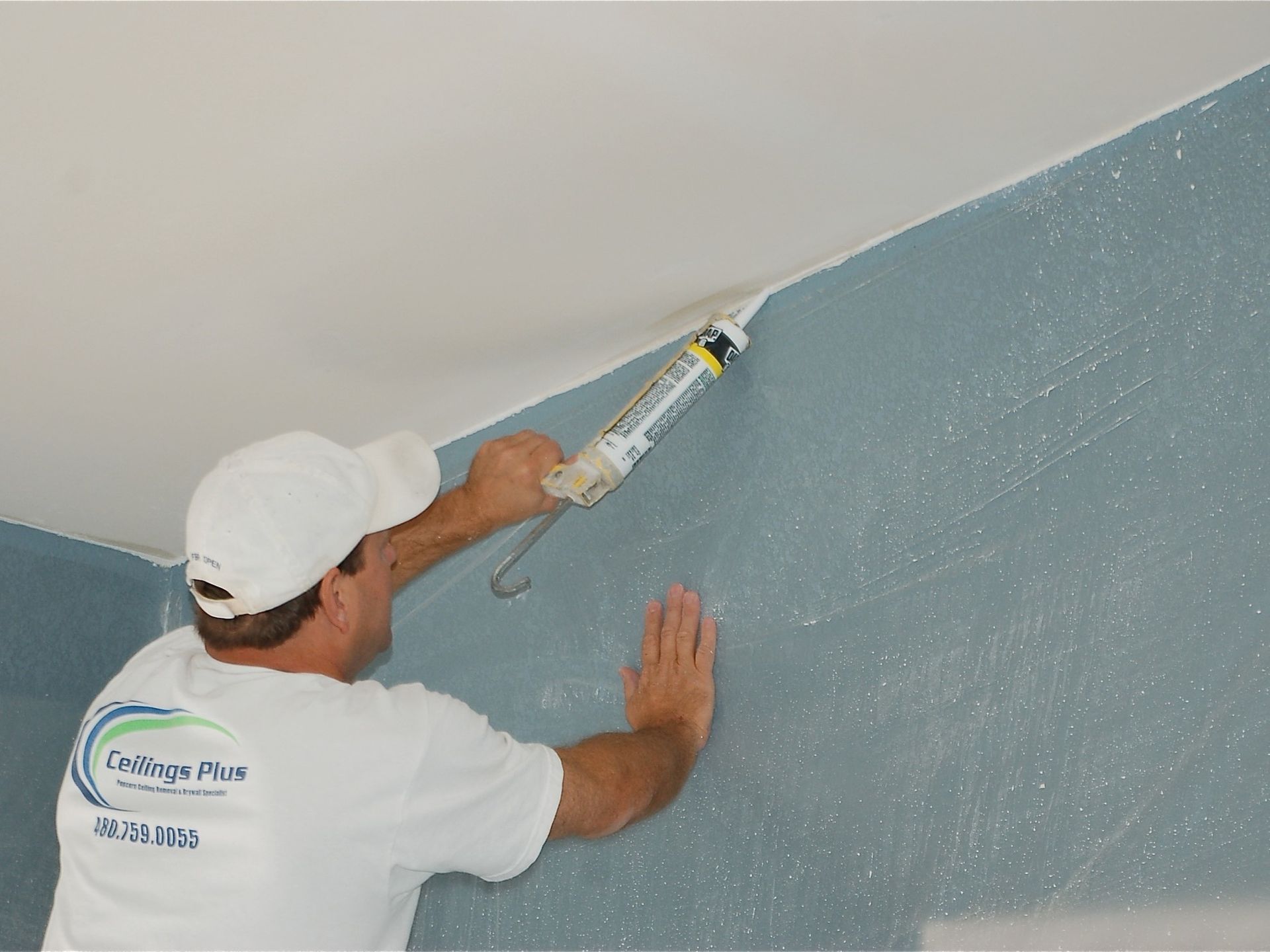 A man in a white shirt is painting a wall.
