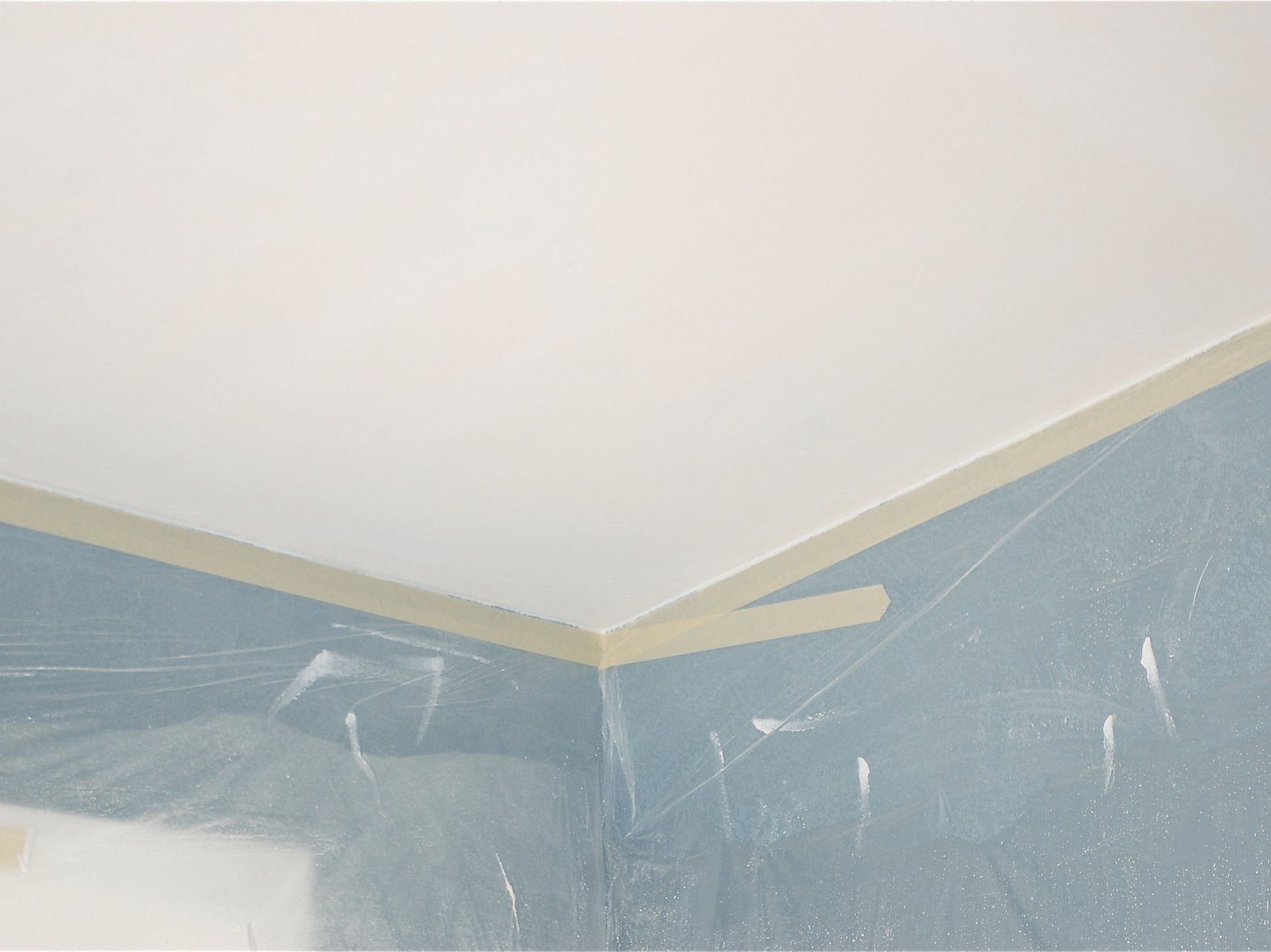 A room is being painted and the ceiling is covered in plastic.