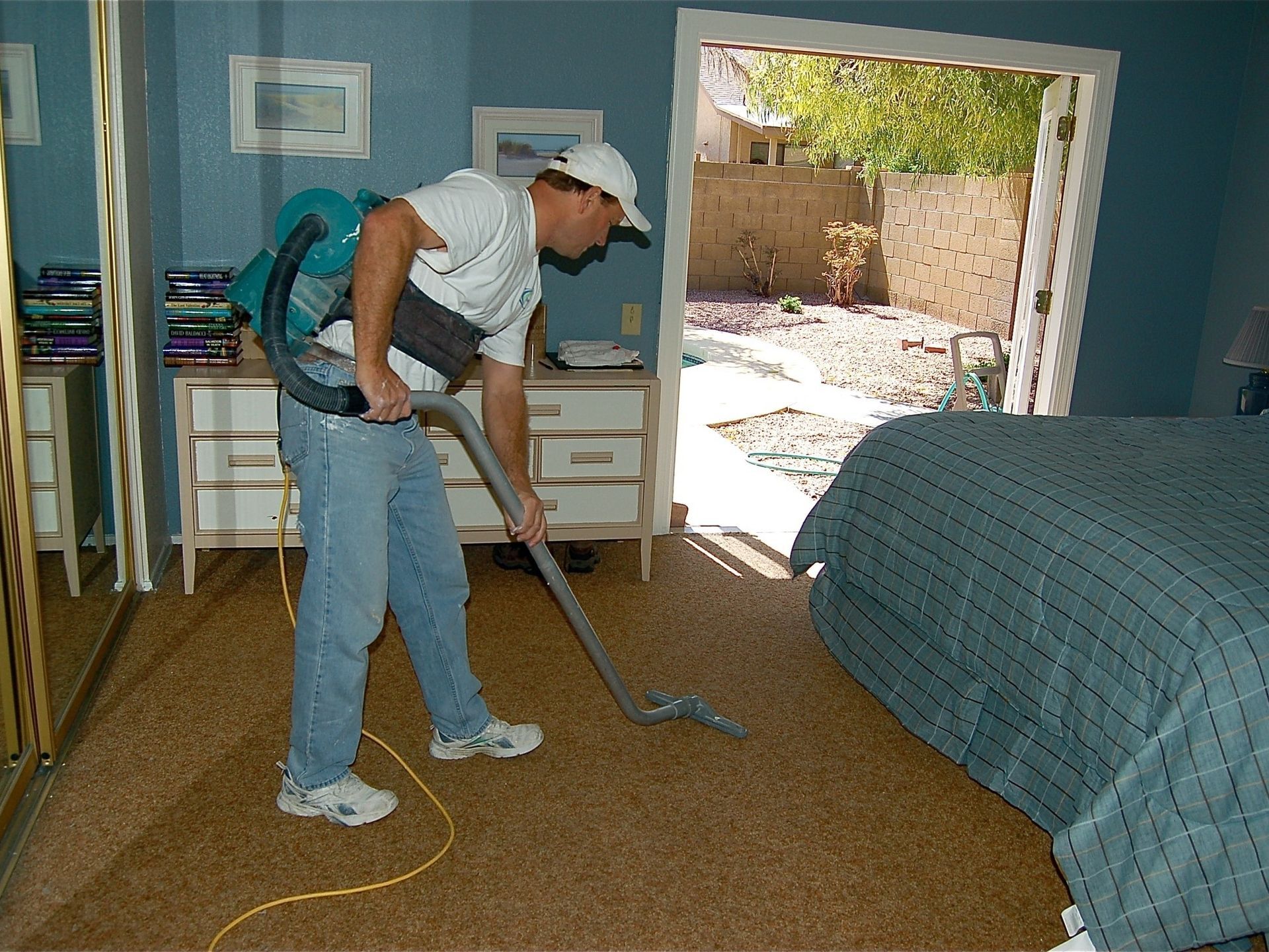 A man is using a vacuum cleaner in a bedroom