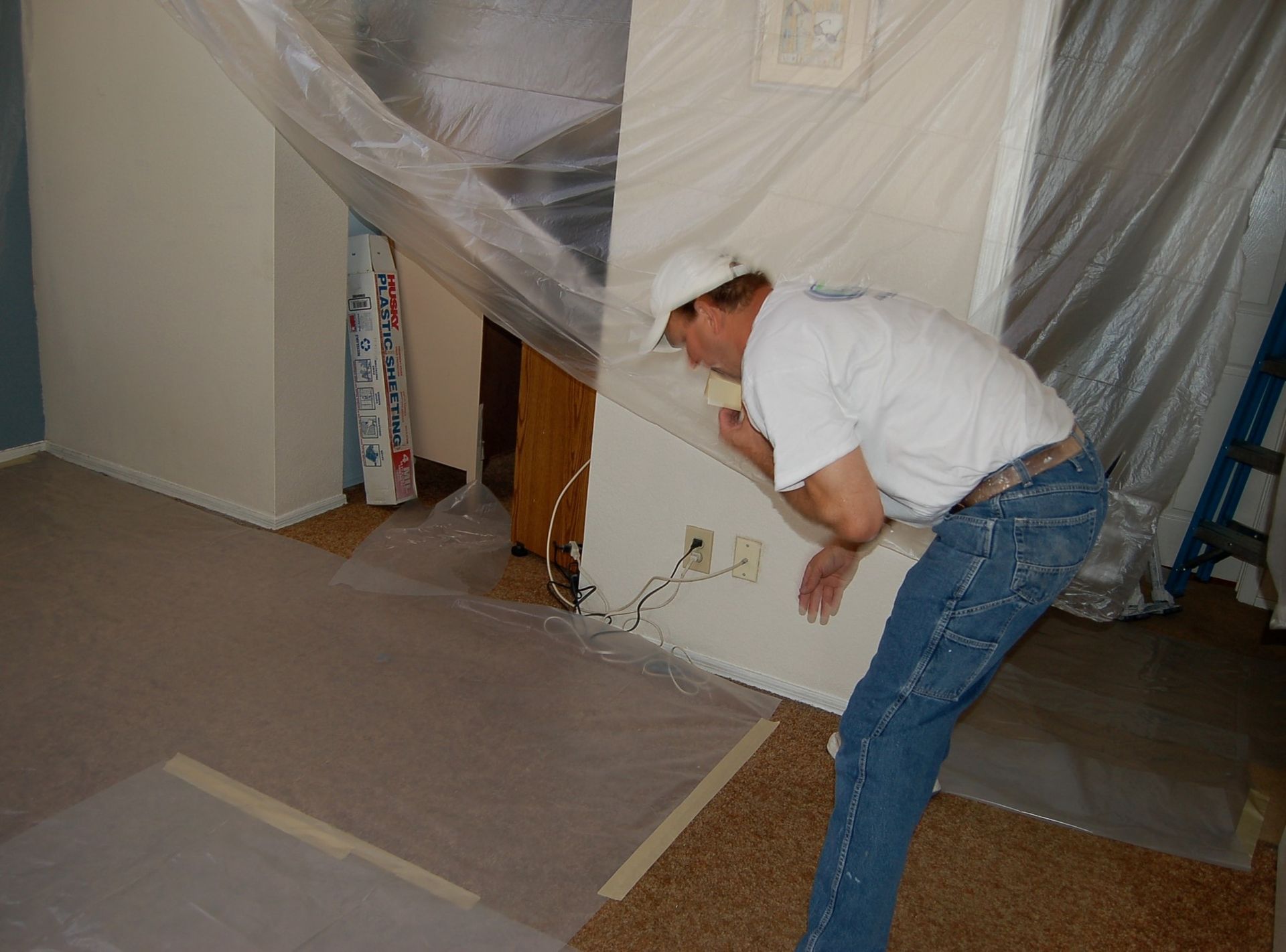 A man is standing in a room with a plastic sheet on the wall.