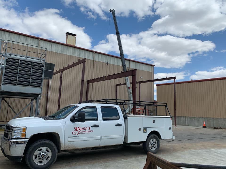 A white truck with a crane on the back is parked in front of a building.