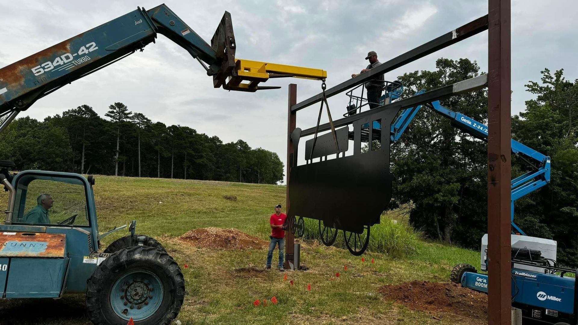 A tractor is lifting a large sign in a field.
