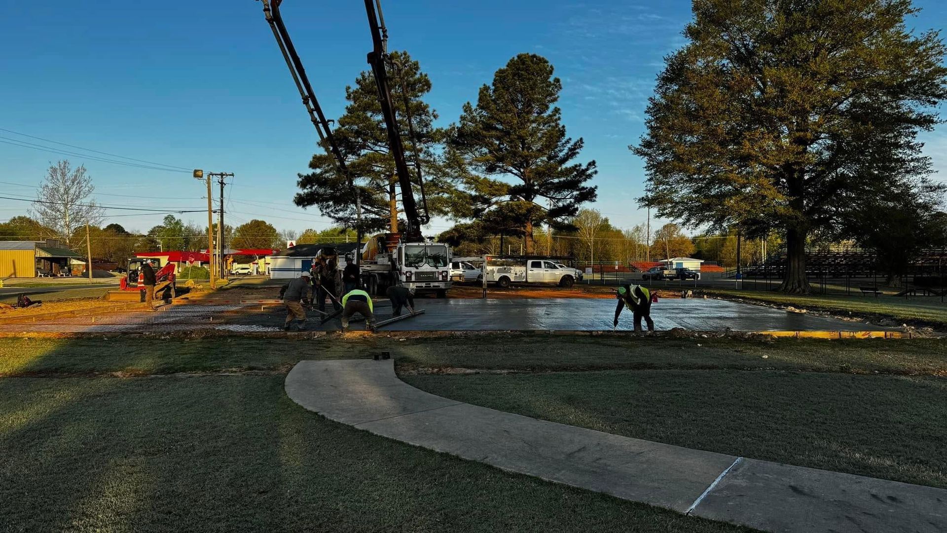 A group of people are working on a concrete walkway in a park.