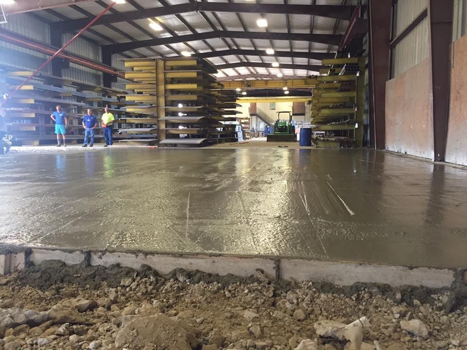 A warehouse with a concrete floor and people standing in the background