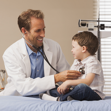 A doctor is listening to a child 's heartbeat with a stethoscope