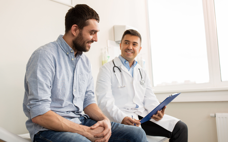 A man is sitting on a bed talking to a doctor.