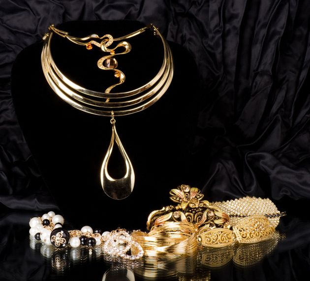 Gold necklace and matching jewelry set on black fabric background