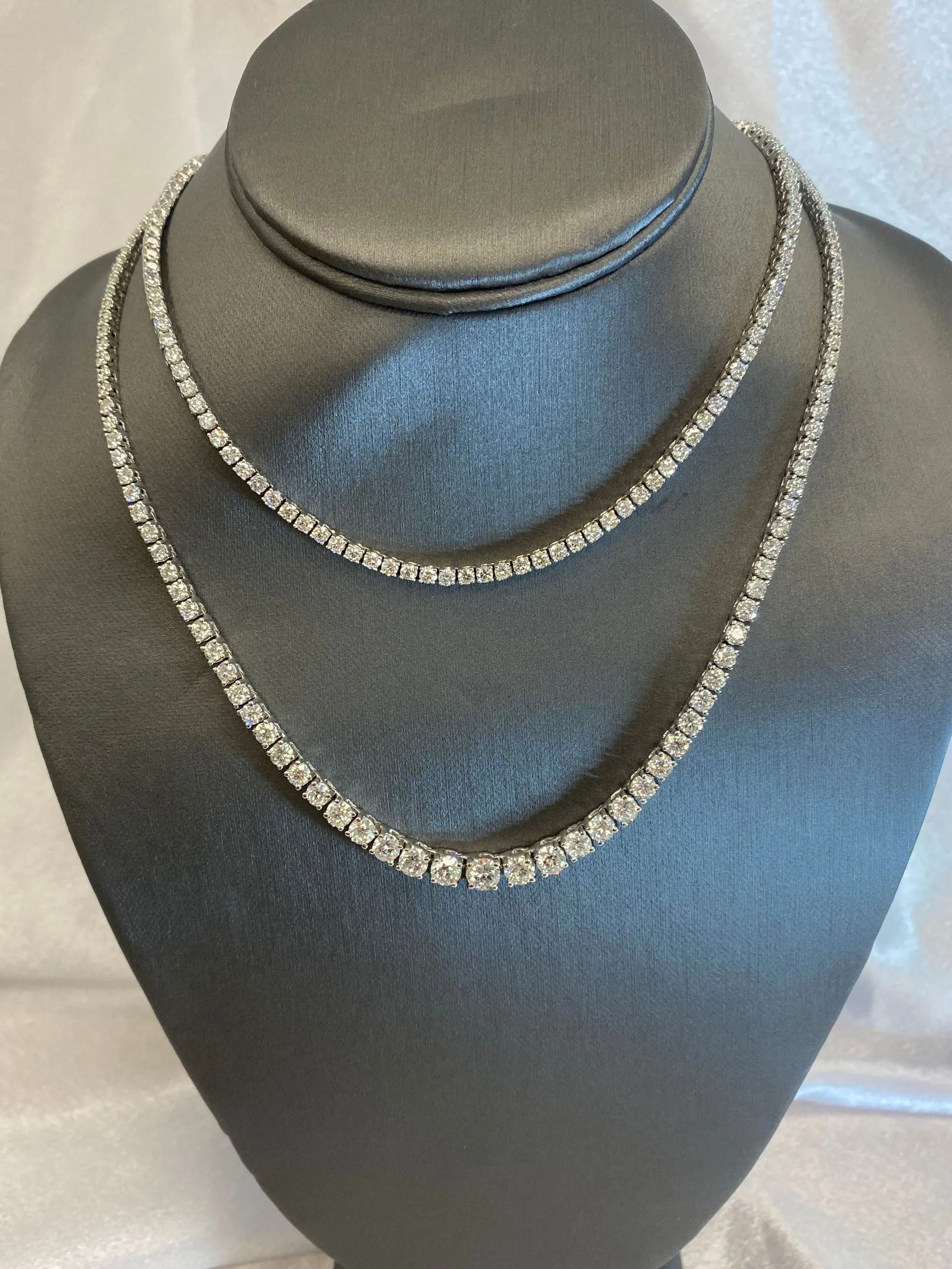 Two layered silver necklaces on a black necklace display bust